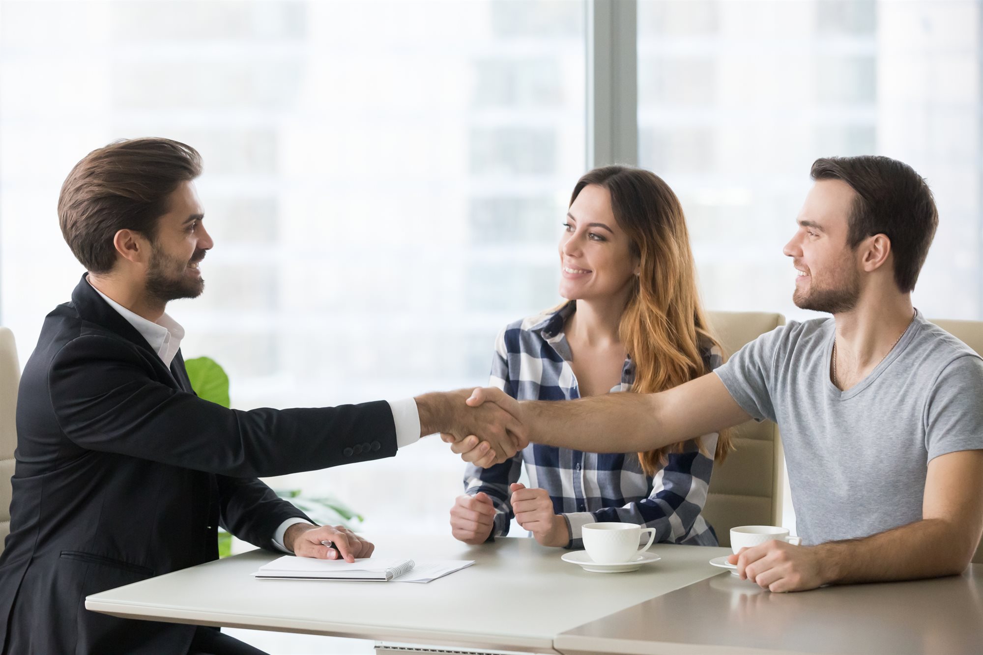 Happy clients shaking hands with an advisor